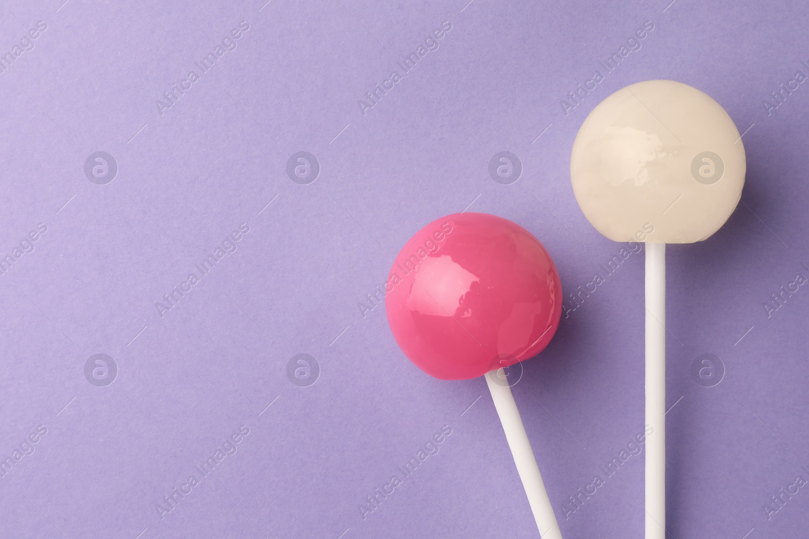 Photo of Tasty lollipops on violet background, flat lay. Space for text