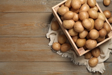 Raw fresh organic potatoes on wooden background, top view. Space for text