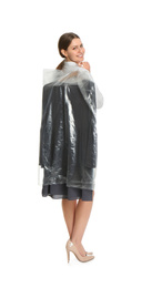 Photo of Young woman holding hanger with dress in plastic bag on white background. Dry-cleaning service