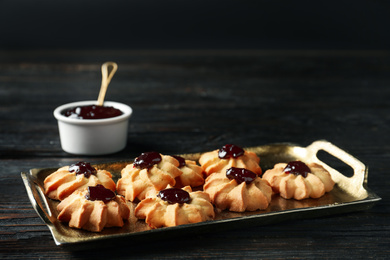 Photo of Tasty shortbread cookies with jam on black wooden table