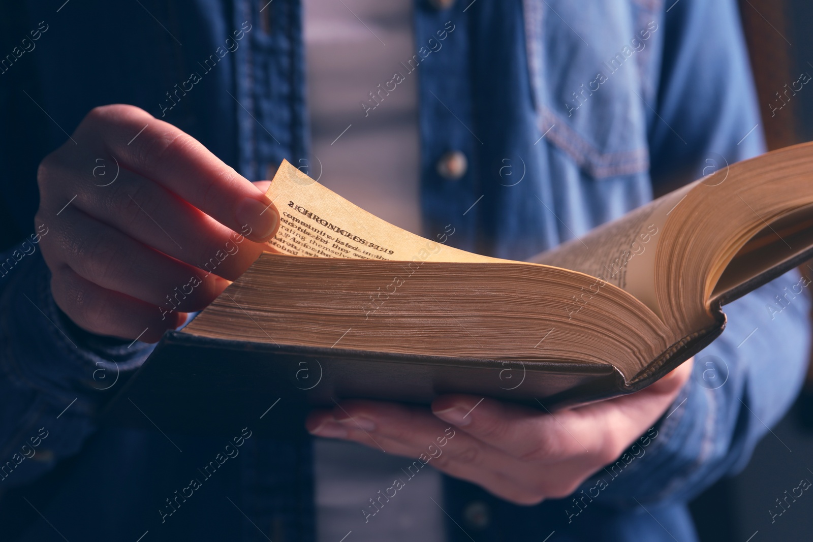 Photo of Woman reading Bible against black background, closeup