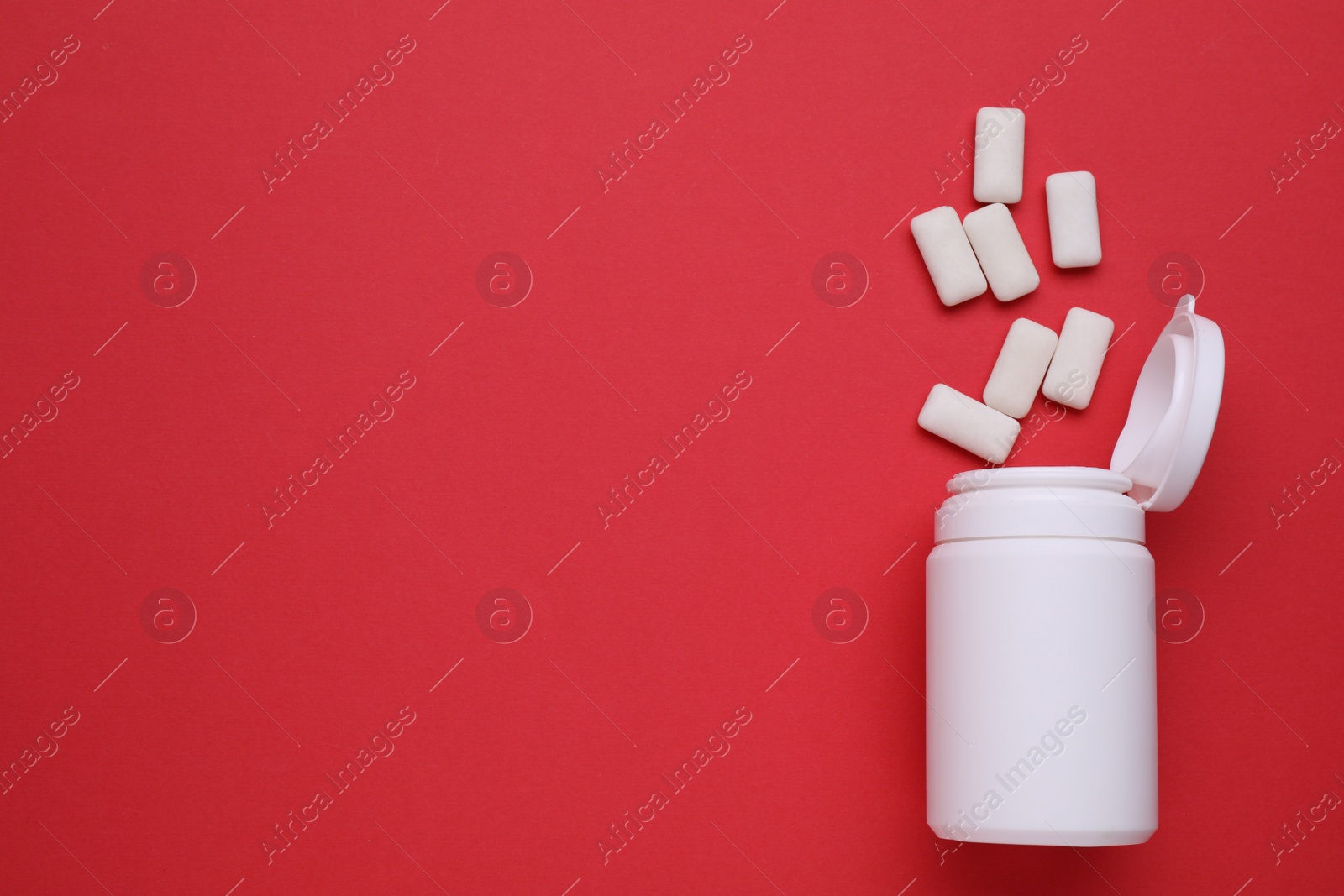 Photo of Jar with chewing gums on red background, flat lay. Space for text