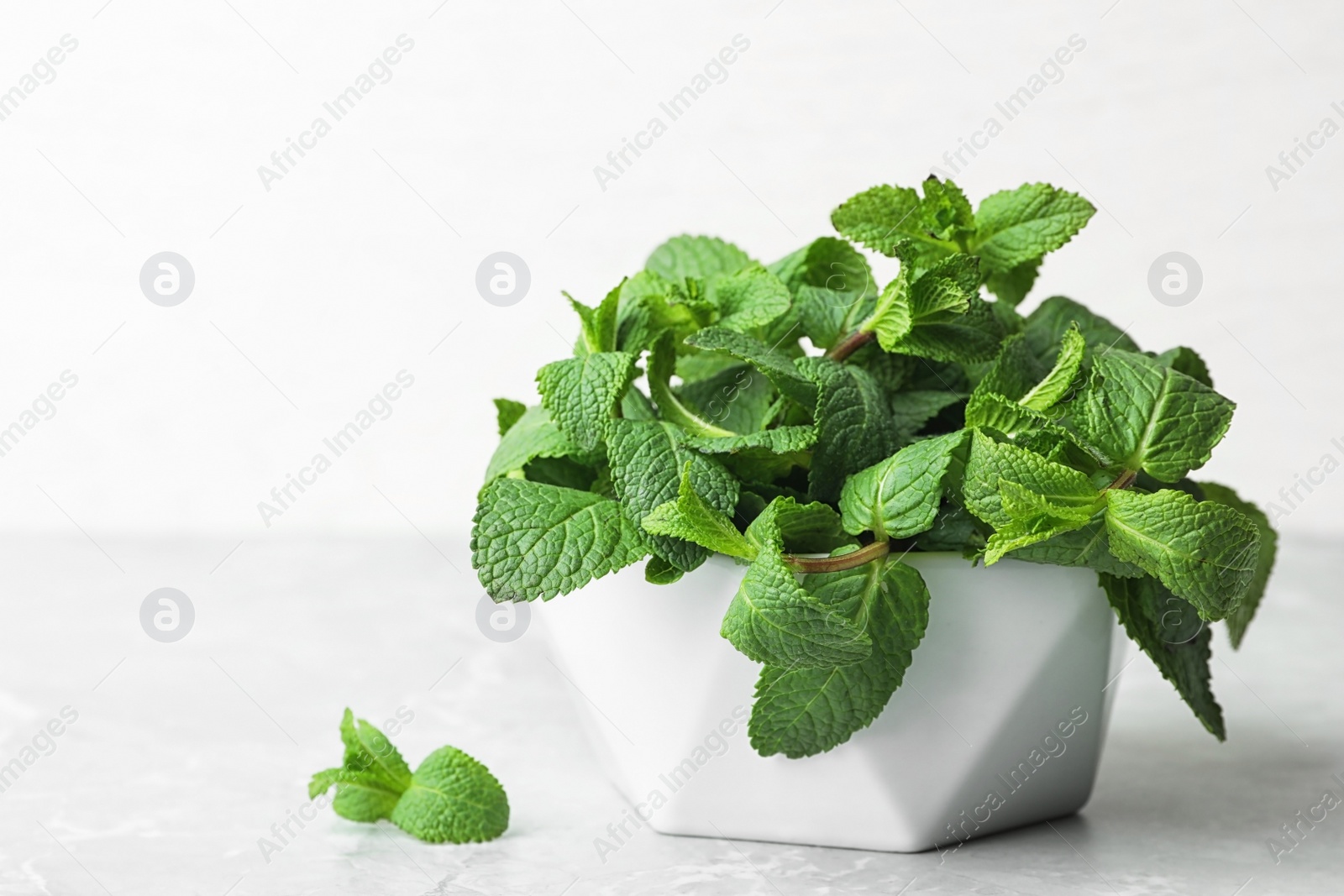 Photo of Bowl with fresh green mint on table. Space for text