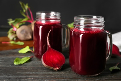 Photo of Fresh beet juice and raw vegetable on dark wooden table
