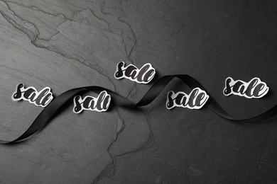 Ribbon and words Sale on dark background, flat lay