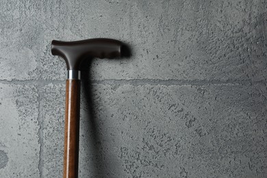 Elegant walking cane on grey stone background, closeup. Space for text