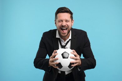 Photo of Emotional sports fan with ball celebrating on light blue background