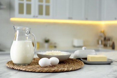 Different dairy products and eggs on white table in modern kitchen. Space for text