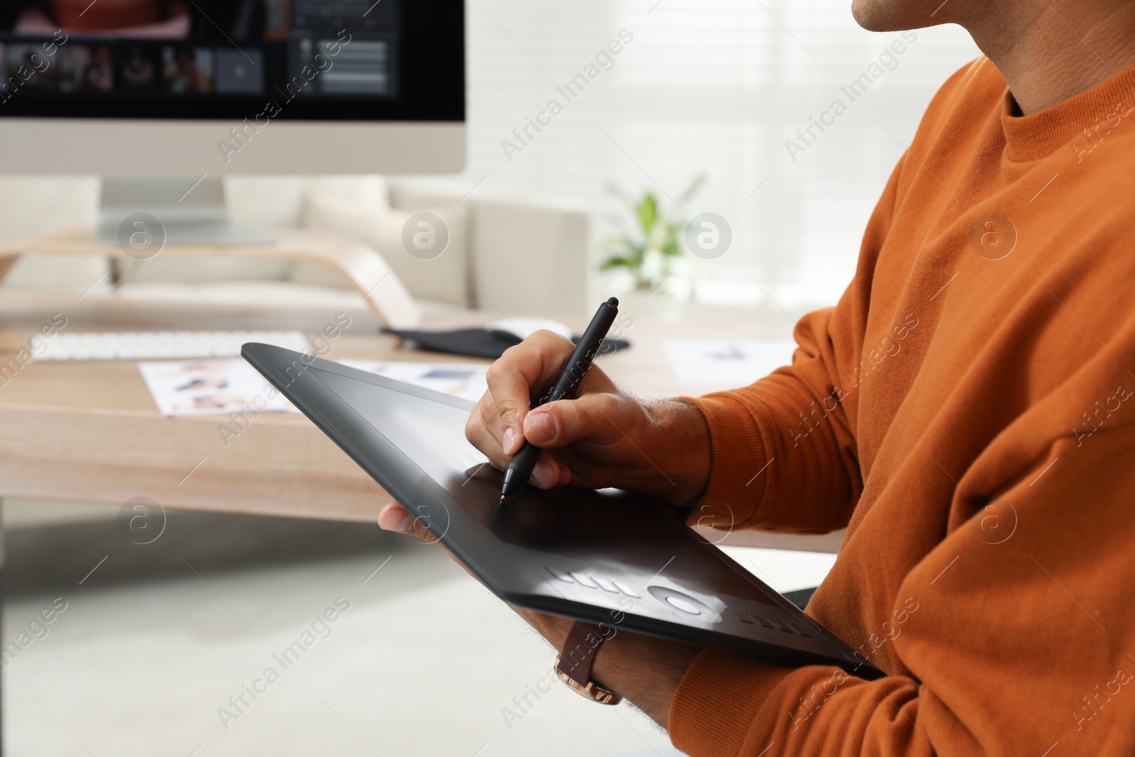 Photo of Professional retoucher working with graphic tablet at desk in office, closeup