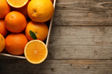 Many whole and cut ripe oranges on wooden table, top view. Space for text