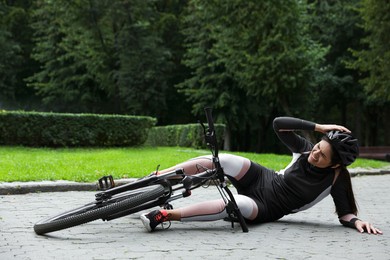 Young woman fallen off her bicycle in park