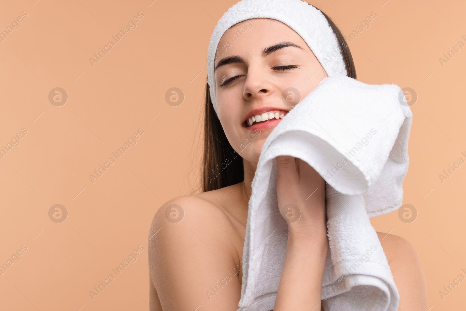 Photo of Washing face. Young woman with headband and towel on beige background, space for text