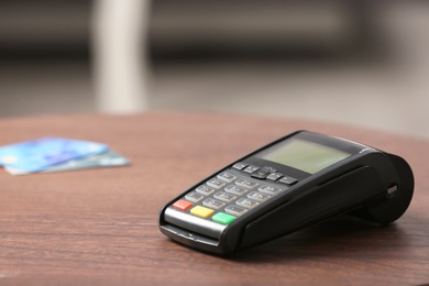 Modern payment terminal on table indoors. Space for text