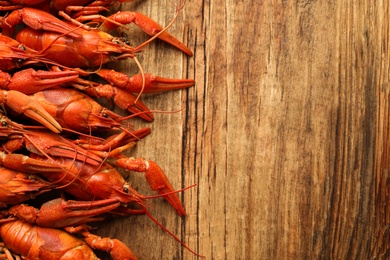 Delicious boiled crayfishes on wooden table, flat lay. Space for text