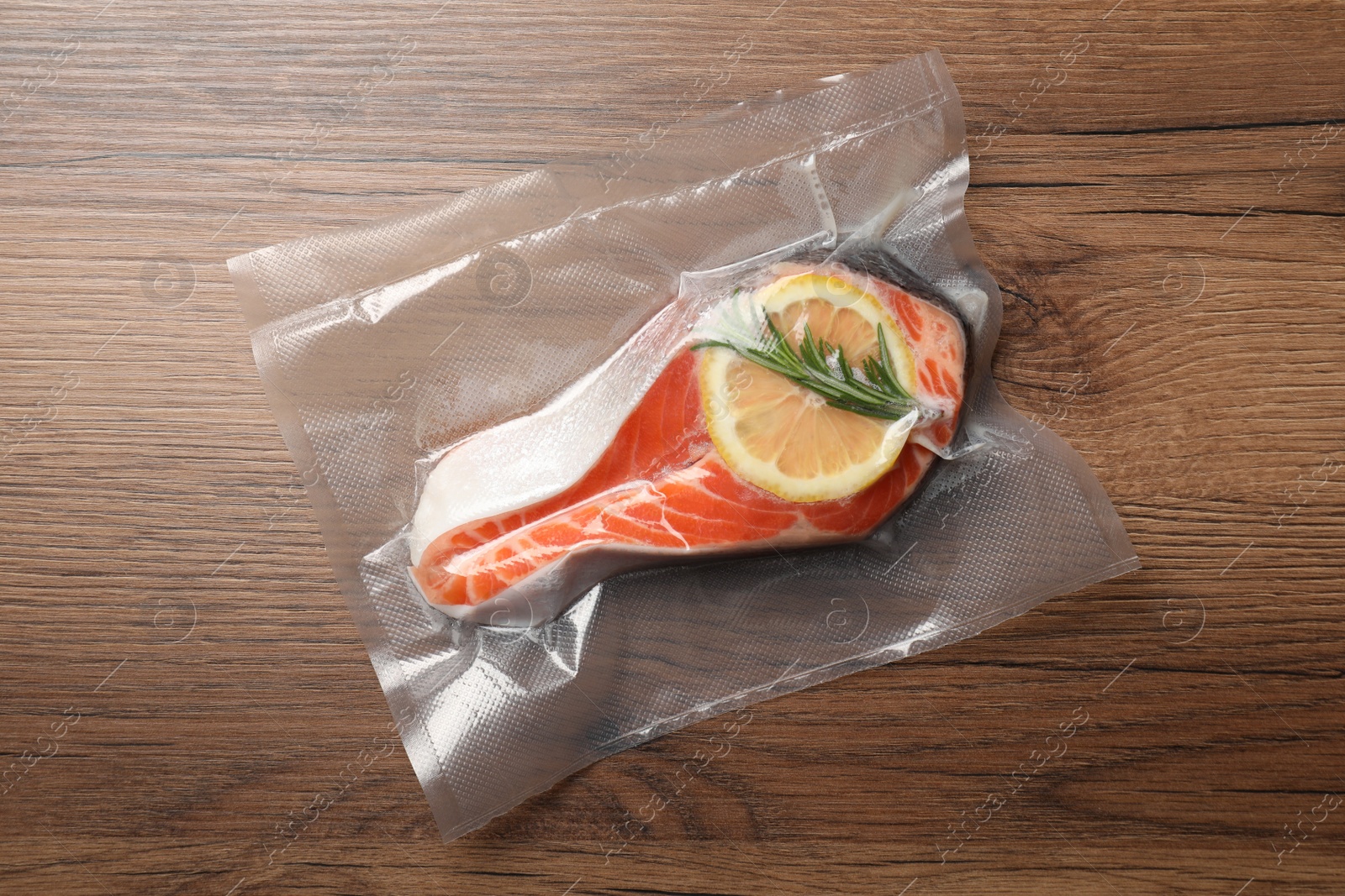 Photo of Salmon with lemon in vacuum pack on wooden table, top view