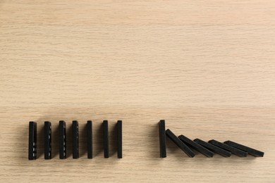 Black domino tiles on wooden background, flat lay. Space for text