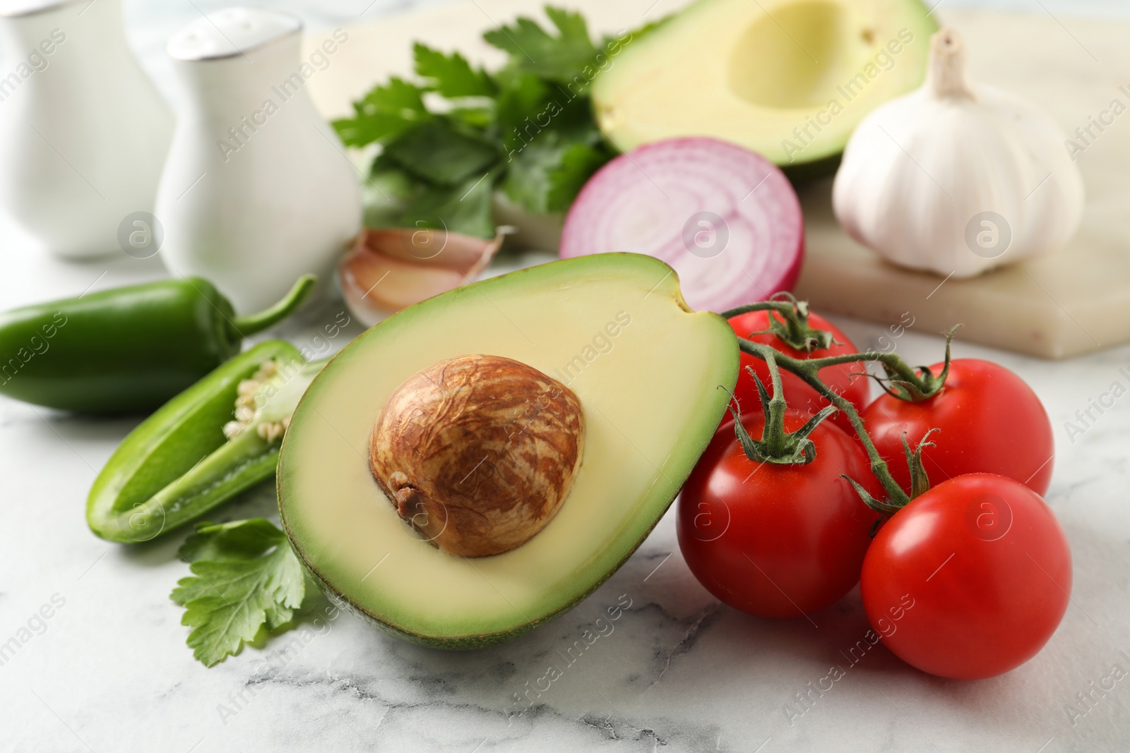 Photo of Fresh ingredients for guacamole on white marble table, closeup