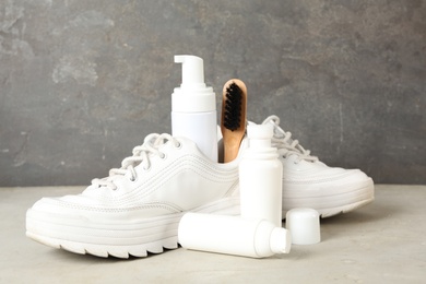 Composition with stylish footwear and shoe care accessories on white table against grey background