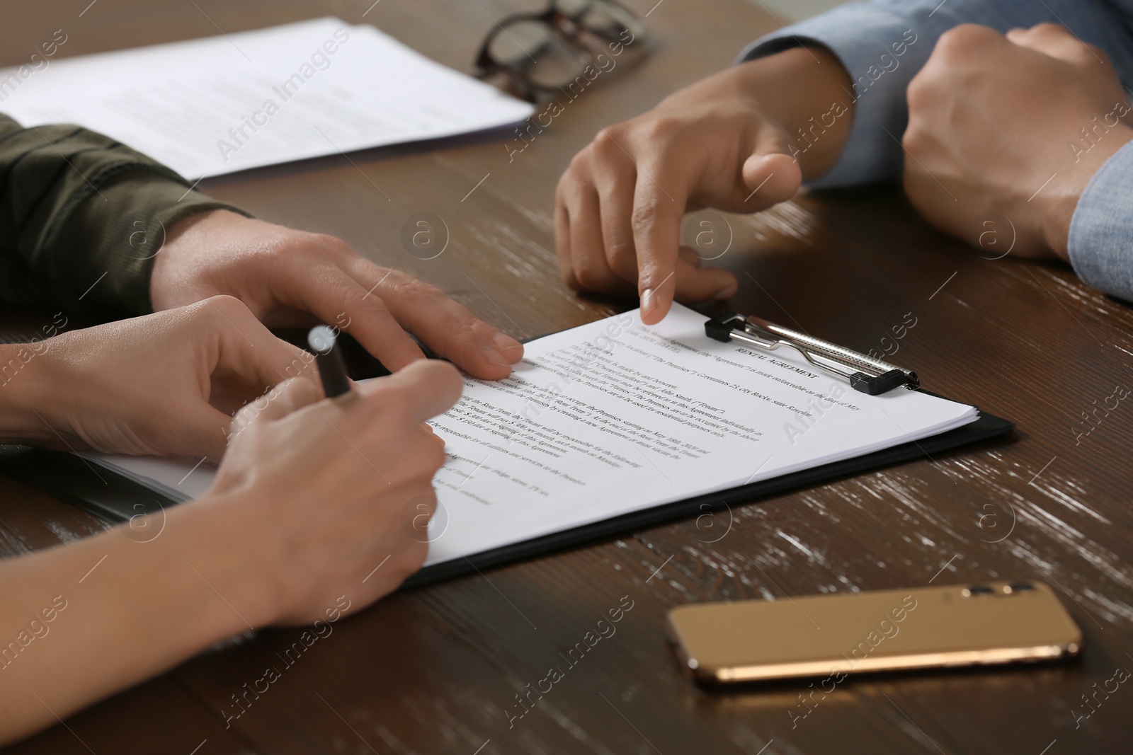 Photo of Notary working with couple at wooden table, closeup