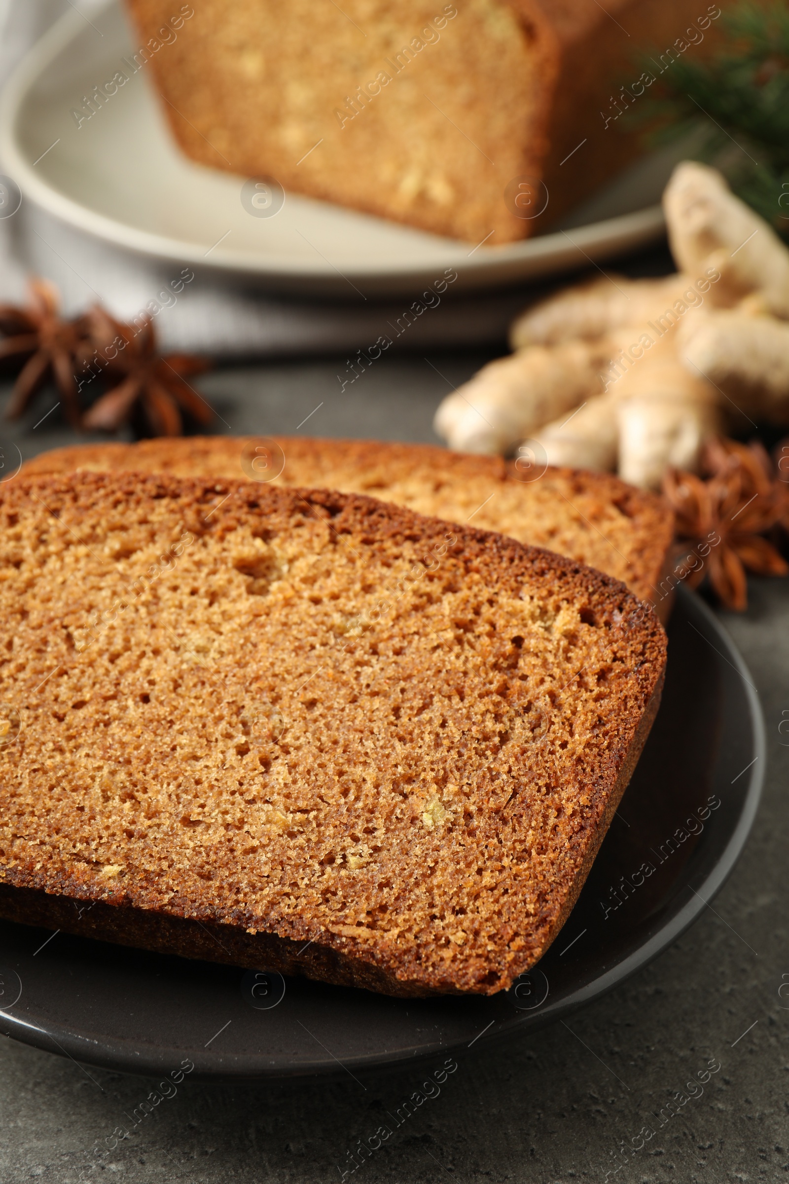 Photo of Fresh gingerbread cake slices served on grey table, closeup