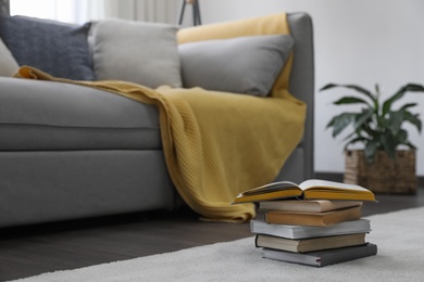 Photo of Stack of books near sofa in living room. Interior design