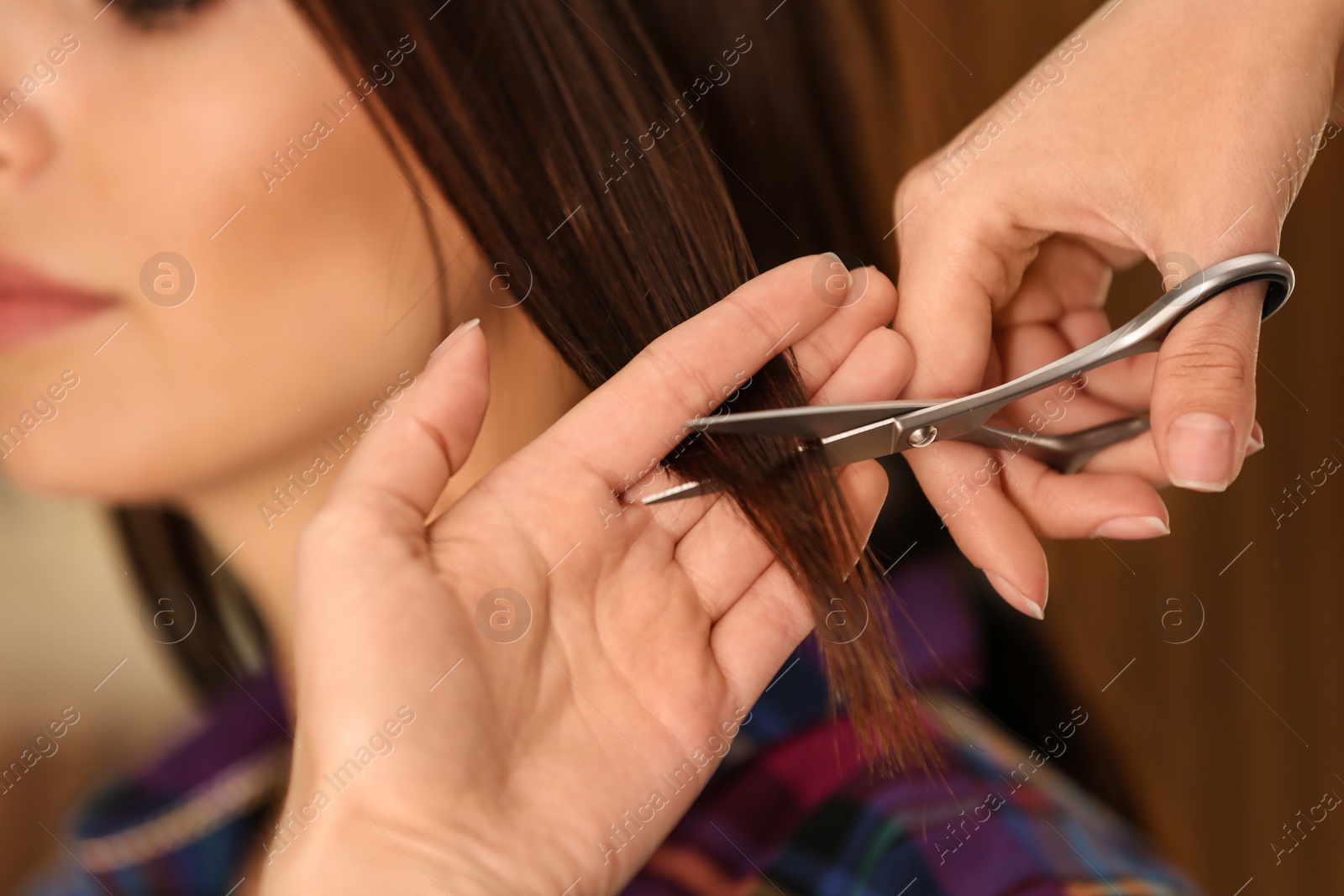 Photo of Barber making stylish haircut with professional scissors in beauty salon, closeup