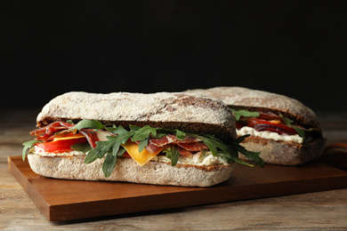 Photo of Delicious sandwich with fresh vegetables and prosciutto on wooden table