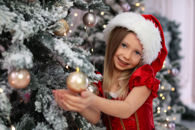 Photo of Cute little child near Christmas tree at home