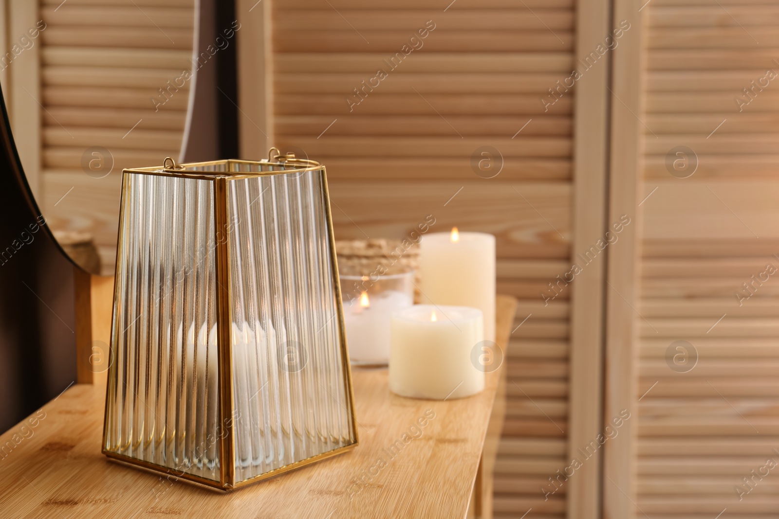 Photo of Stylish holder with burning candle on wooden table indoors. Space for text