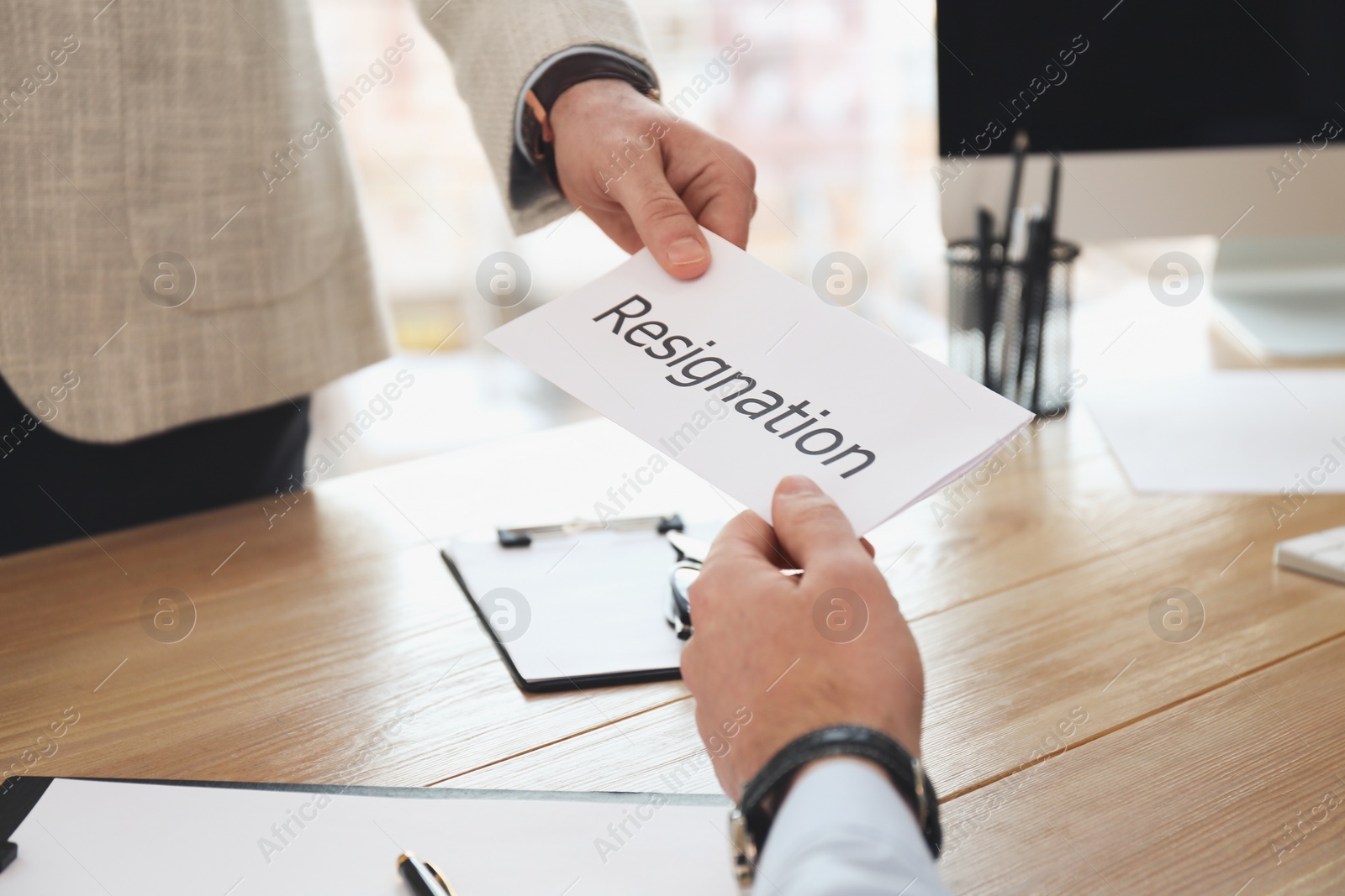 Photo of Employee giving resignation letter to boss in office, closeup