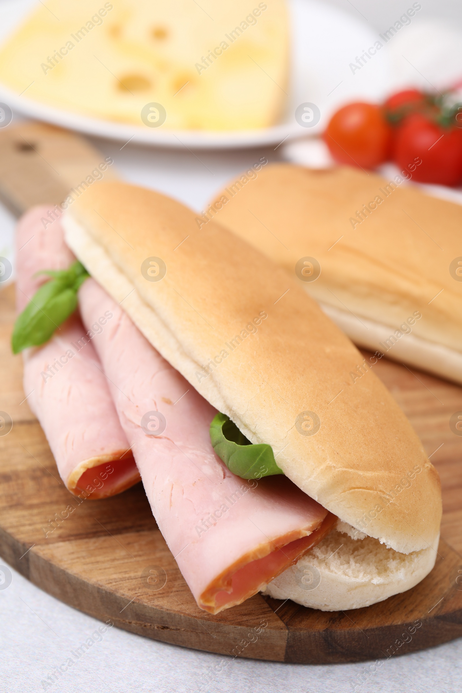 Photo of Delicious sandwich with ham and basil on white table, closeup