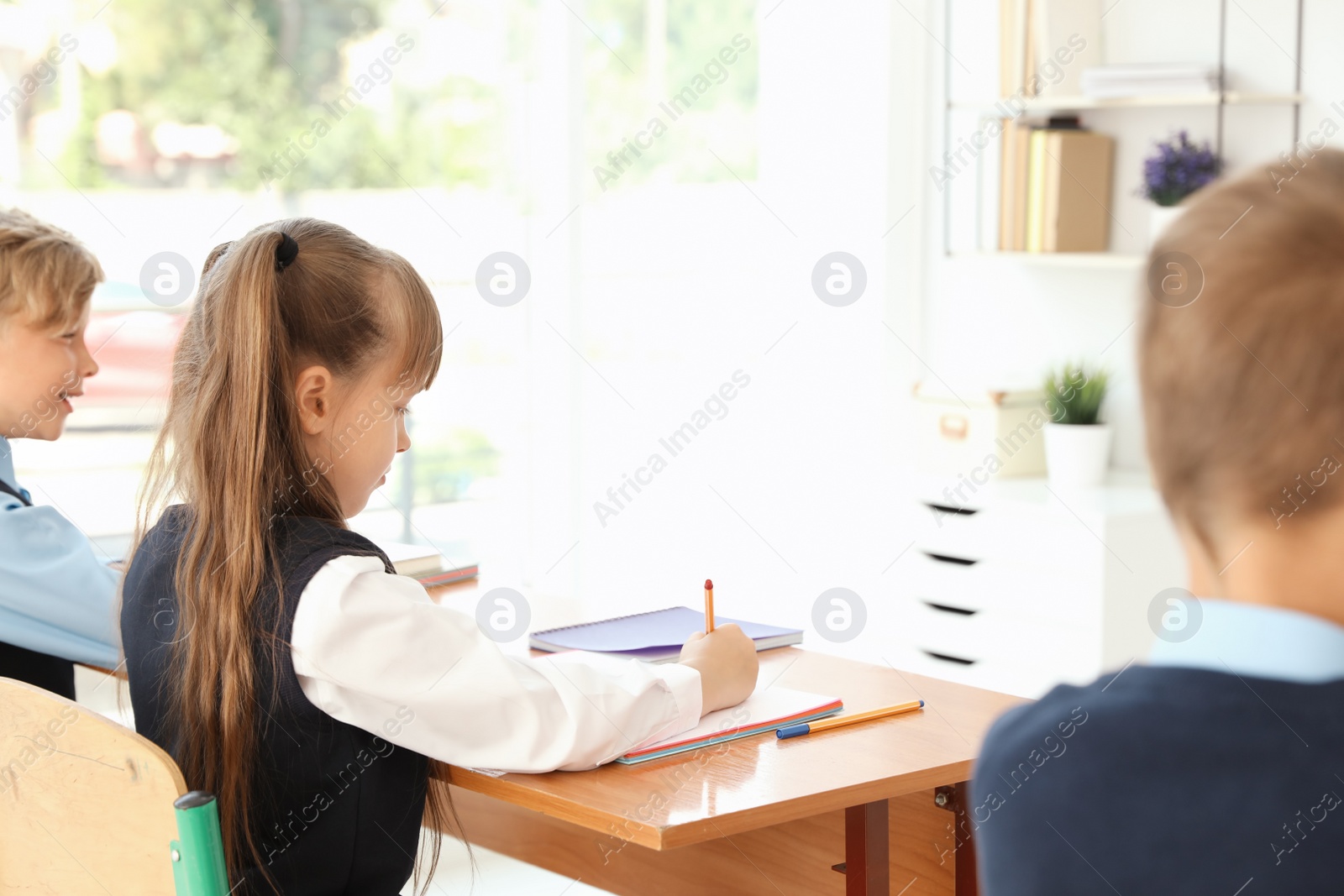 Photo of Little children in classroom. Stylish school uniform