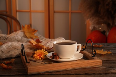 Cup of aromatic tea with sugar, flower and autumn leaves on wooden table indoors