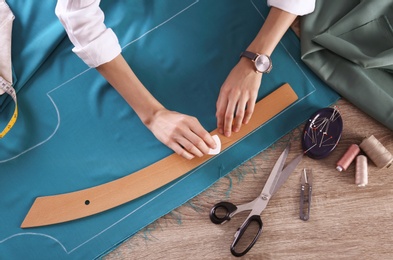 Tailor working with cloth at table in atelier, top view