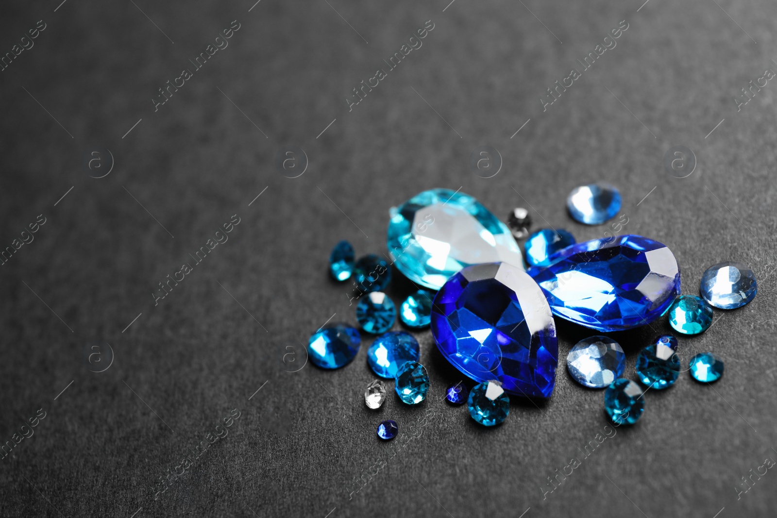 Photo of Pile of different beautiful gemstones on black background. Space for text