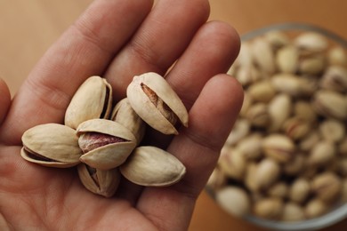 Photo of Woman holding pile of pistachio nuts, top view