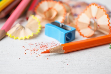 Photo of Color pencils, sharpener and shavings on white table, closeup
