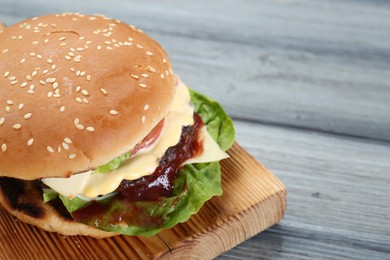 Tasty homemade cheeseburger with lettuce on grey wooden table, closeup. Space for text
