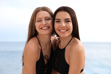 Young woman in bikini with girlfriend on beach. Lovely couple