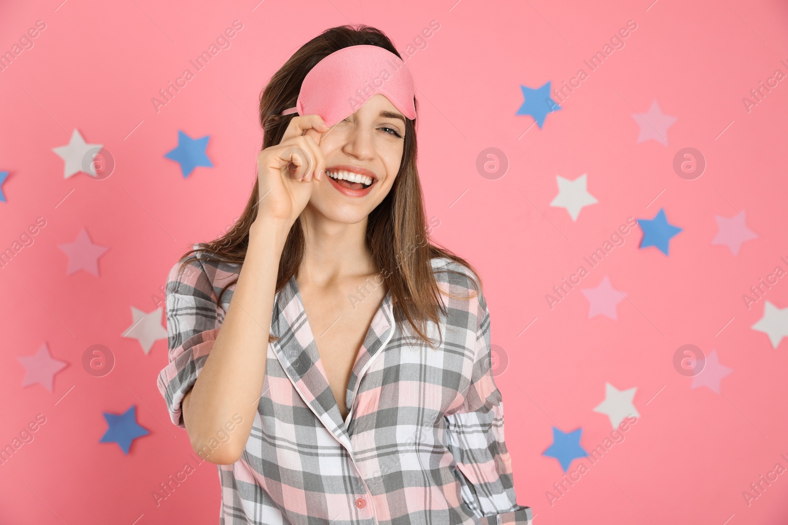 Photo of Beautiful woman wearing pajamas and sleep mask on pink background. Bedtime