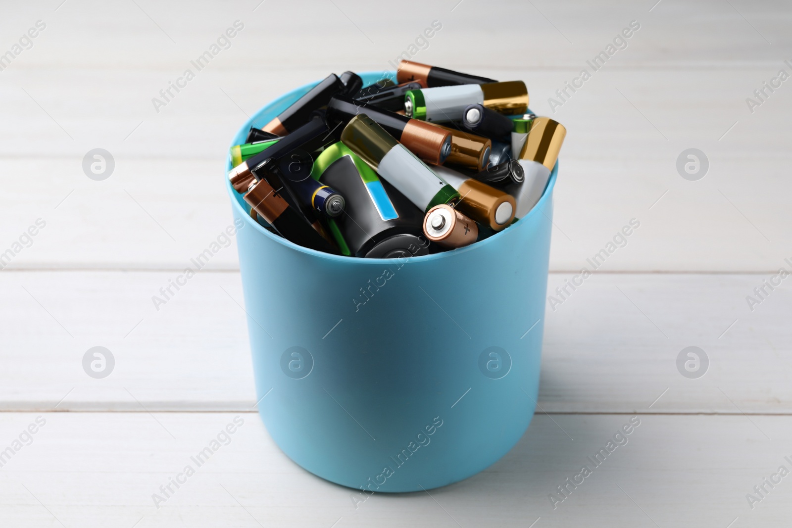 Image of Used batteries in bucket on white wooden table