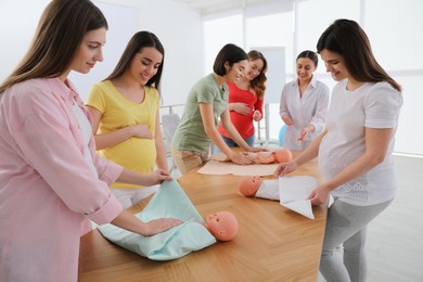 Pregnant women learning how to swaddle baby at courses for expectant mothers indoors