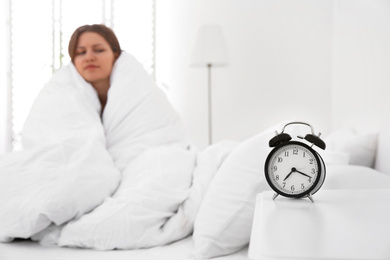 Alarm clock and young woman at home in morning