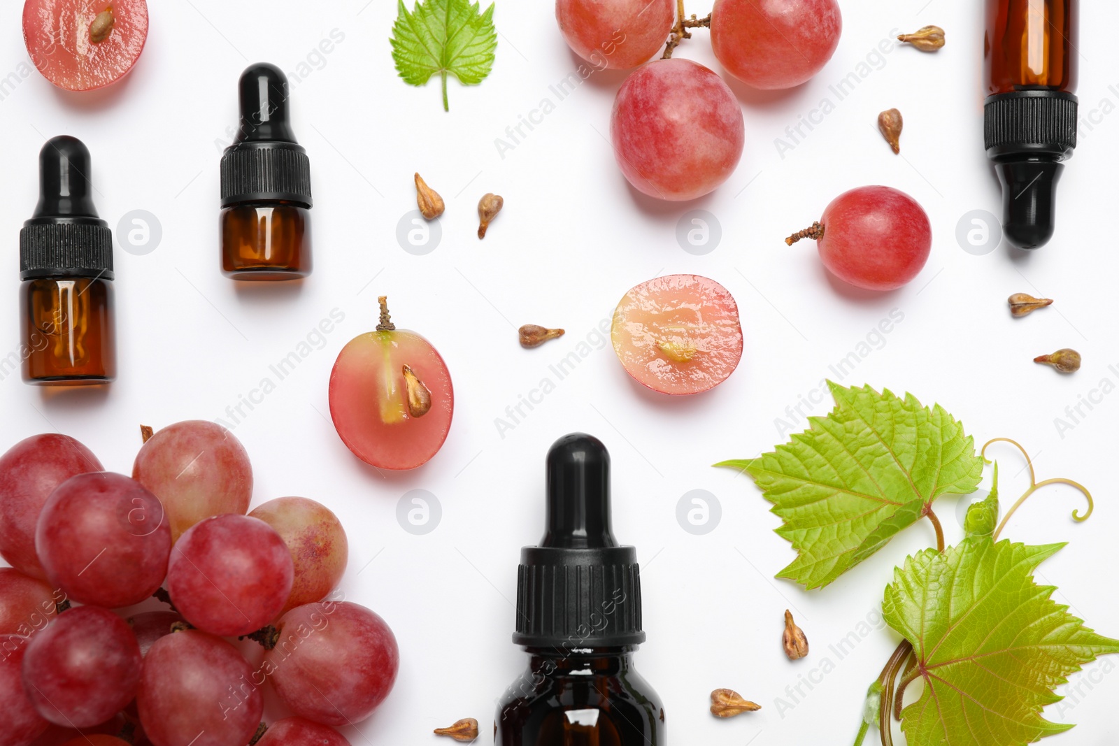 Photo of Composition with bottles of natural grape seed oil on white background, top view. Organic cosmetic