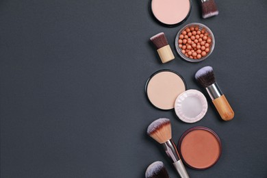 Different face powders and makeup brushes on black background, flat lay. Space for text