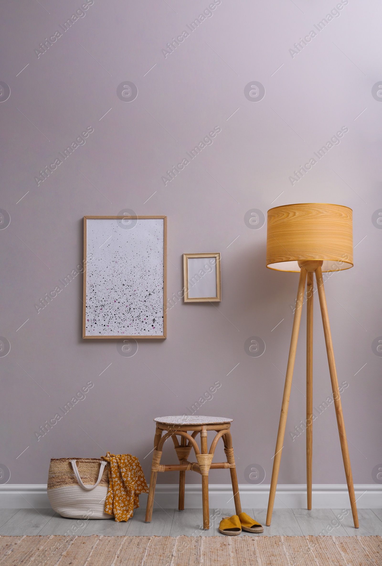 Photo of Wooden stool, lamp and bag near light grey wall indoors. Interior accessories