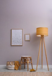 Photo of Wooden stool, lamp and bag near light grey wall indoors. Interior accessories