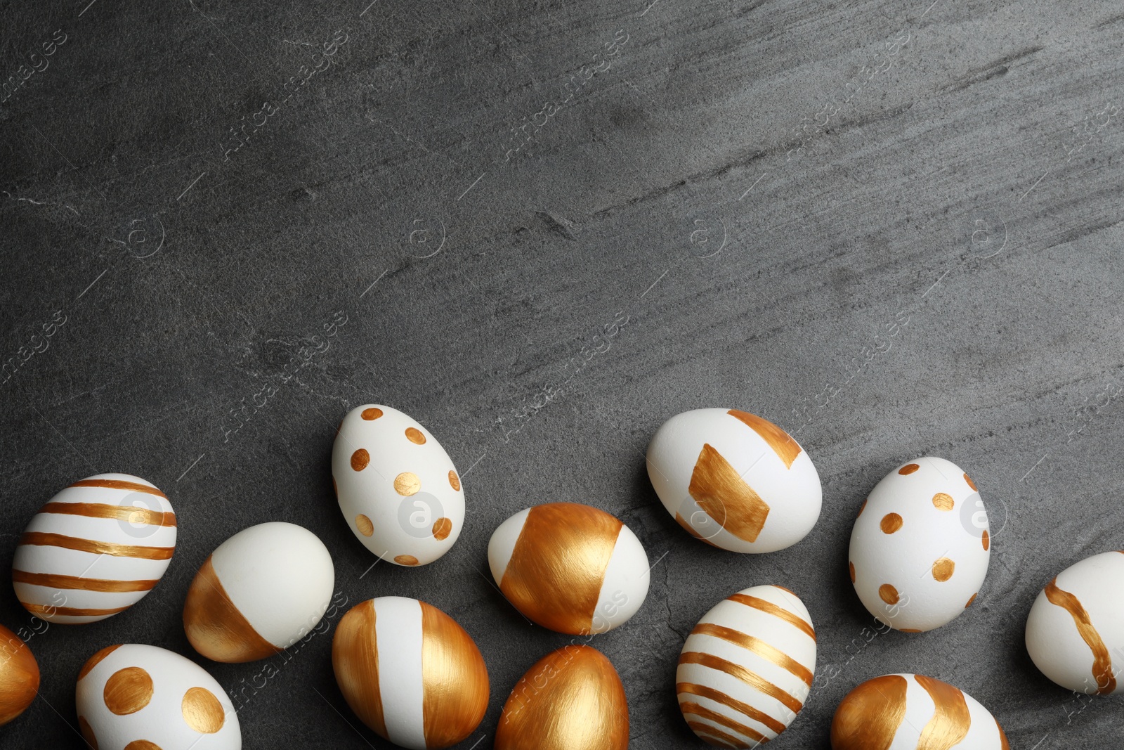 Photo of Flat lay composition of traditional Easter eggs decorated with golden paint on grey background, space for text