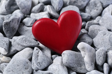 Photo of Red decorative heart on grey stones, closeup