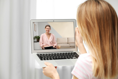 Woman using laptop at home for online consultation with psychologist via video chat, focus on screen